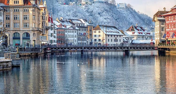 Bâtiments de la vieille ville saupoudrés de neige et pont de la Chapelle se reflétant dans la rivière Reuss par un matin d'hiver à Lucerne.