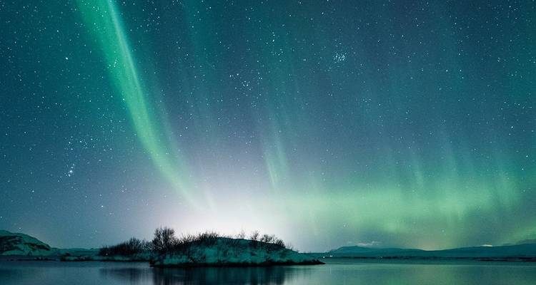Northern lights over a tranquil body of water at night.