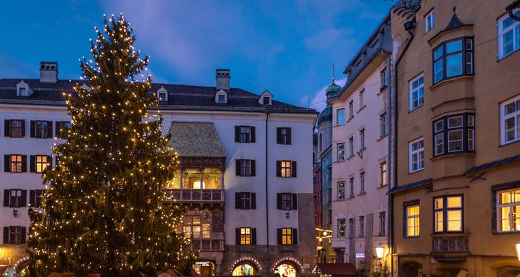 Scène de marché de Noël avec un grand sapin de Noël décoré et des bâtiments historiques.