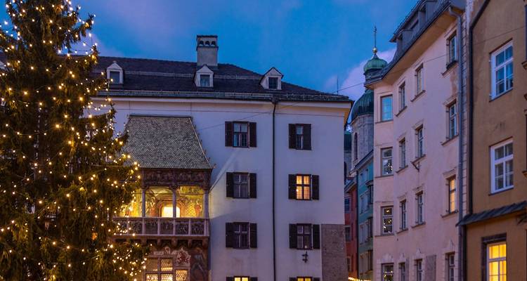 Scène crépusculaire des lumières d'un sapin de Noël décoré à côté de bâtiments historiques dans la vieille ville d'Innsbruck.