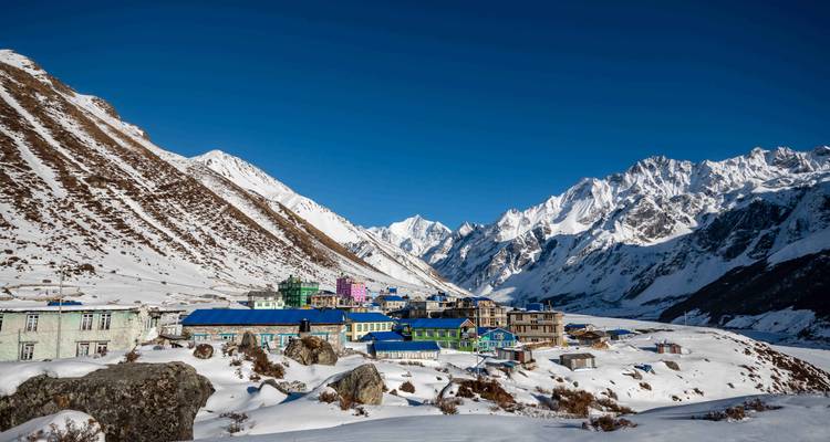 Kleurrijk bergdorp met met sneeuw bedekte toppen op de achtergrond.