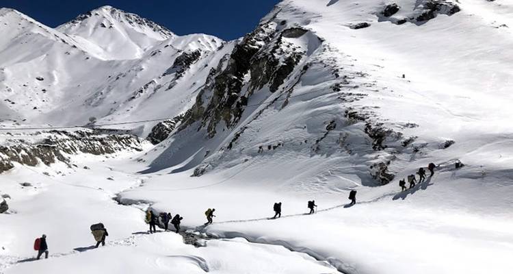 Groep trekkingstochtgangers die een met sneeuw bedekte vallei beklimmen.