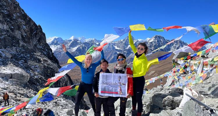 Randonneurs célébrant au sommet d'une montagne avec des drapeaux de prière