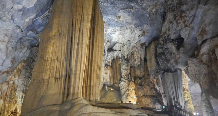 Grandes estalactitas y caminos iluminados en el interior de una vasta cueva.