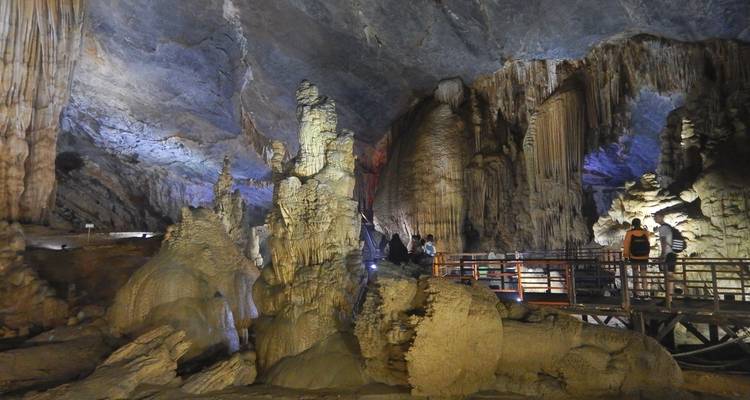 Gran caverna interior con formaciones rocosas y caminos iluminados.