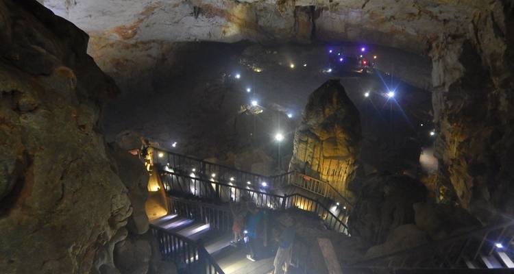 Interior de la cueva iluminado con un camino artificial y estalagmitas.
