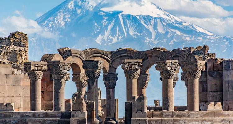 Ancient ruins with snow-capped mountain in the background.