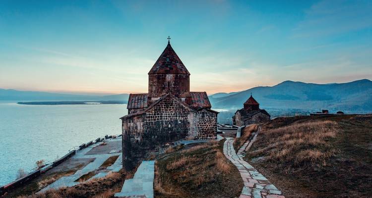 Historic church by a lake during sunset.