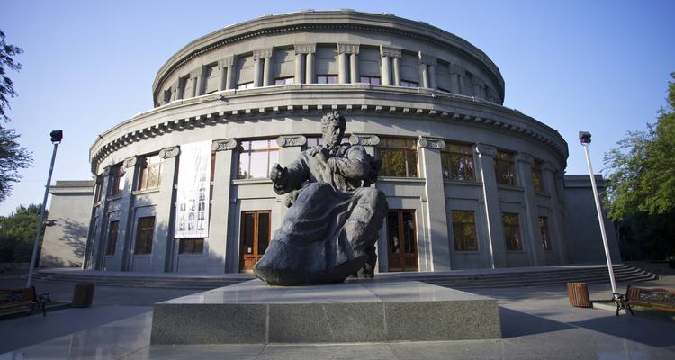 Grand bâtiment rond avec une grande statue devant.