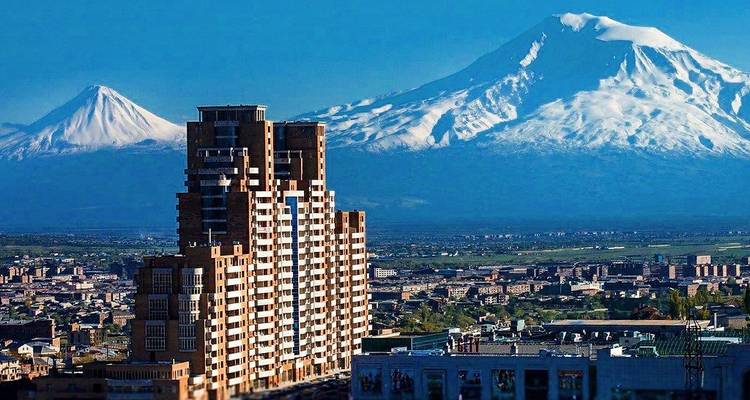 Horizon urbain avec des bâtiments modernes et des montagnes enneigées.
