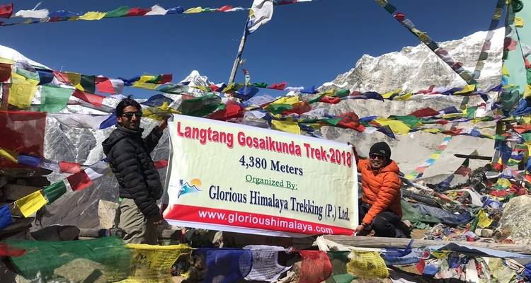 Deux personnes debout près d'un panneau pour le trek de Langtang Gosai Kunda avec un paysage de montagnes en arrière-plan.