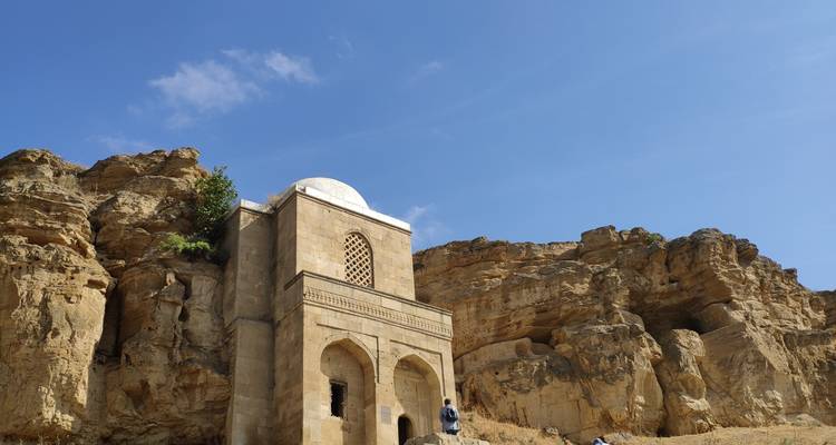 Historic building with a dome set against rocky cliffs.
