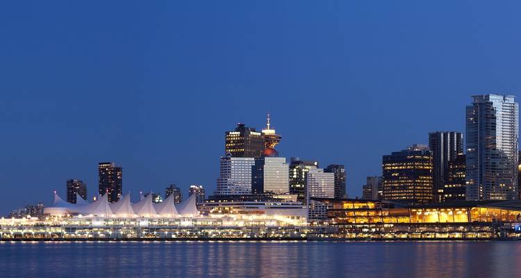Horizon de Vancouver la nuit avec des bâtiments illuminés et leur reflet dans l'eau.