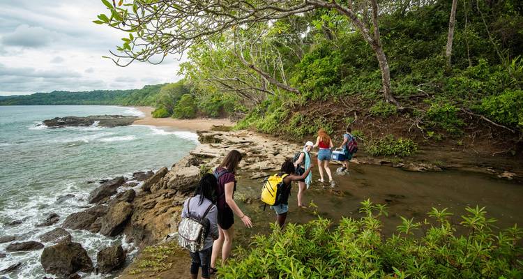 People hiking on a rocky shore with a view of the ocean.