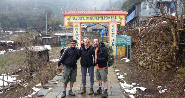 People standing by a Poon Hill sign with snow.