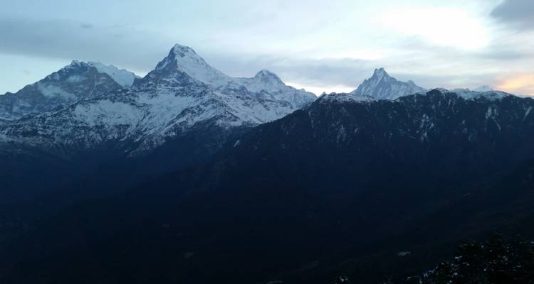 Besneeuwde bergtoppen onder een bewolkte hemel.