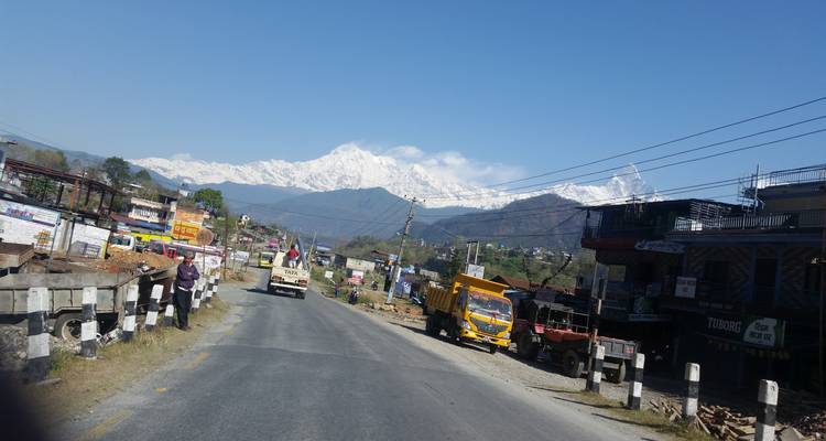 Weg met voertuigen en besneeuwde bergachtergrond.