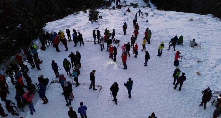 Groep mensen op een besneeuwde heuveltop.