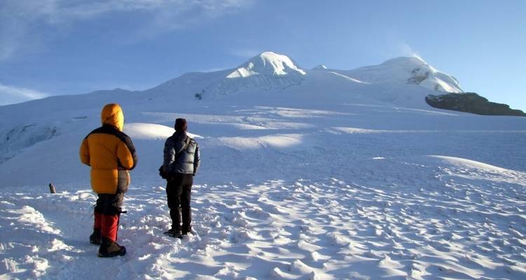 Deux personnes regardant un pic montagneux recouvert de neige.