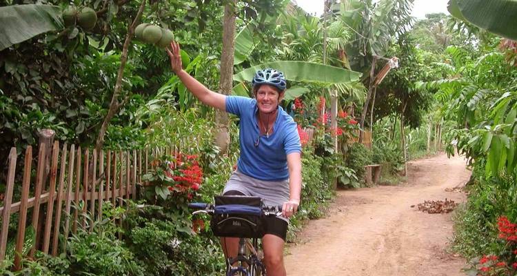 Cycliste traversant un jardin luxuriant et faisant un signe de la main.