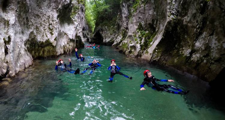 Group of people canyoning in a narrow, clear-water gorge.