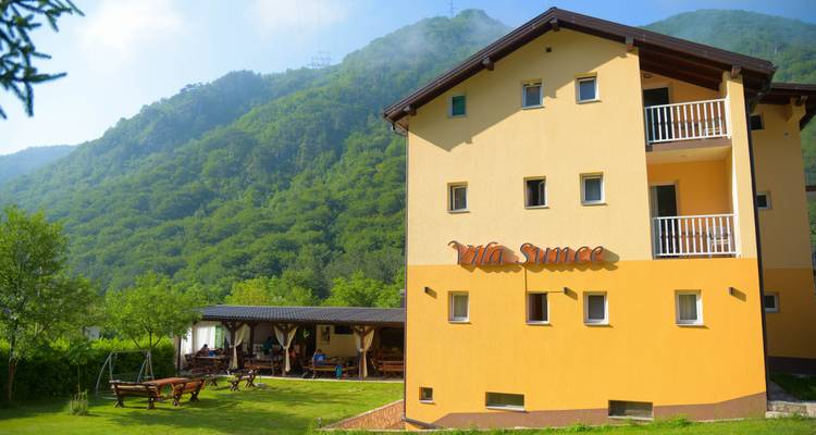 Bright yellow villa in a green mountainous area.
