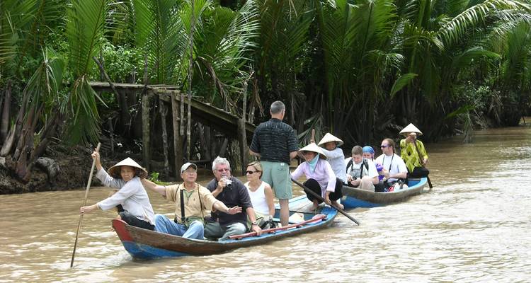Un grupo de personas remando en una embarcación tradicional por un río rodeado de exuberante vegetación.