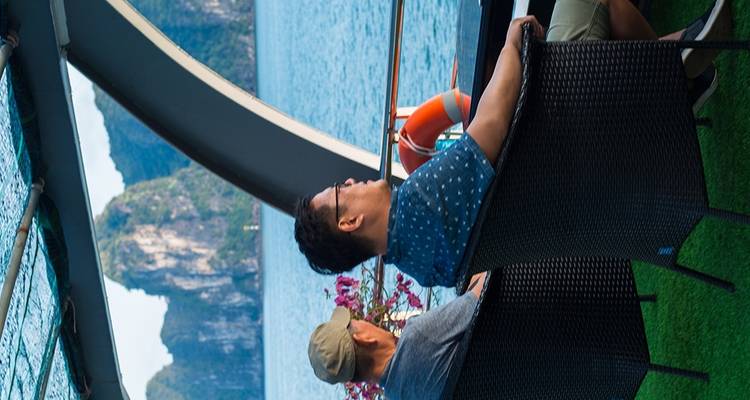 Dos hombres relajándose en una terraza con vista al océano.