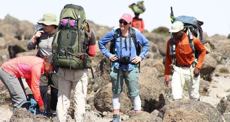 Wanderer, die auf felsigem Gelände rasten, mit einem Berg im Hintergrund.