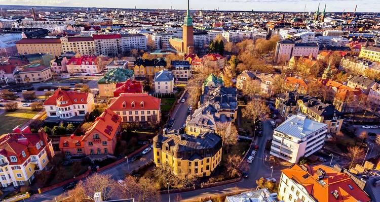 Vista aérea del paisaje urbano de los suburbios de Helsinki con techos coloridos, torres de iglesias y calles arboladas a última hora de la tarde.