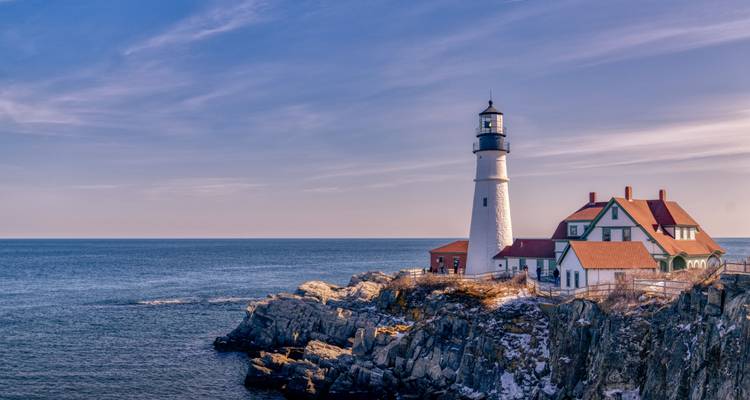 Phare blanc emblématique perché sur des falaises rocheuses surplombant l'océan Atlantique dans une douce lumière matinale.