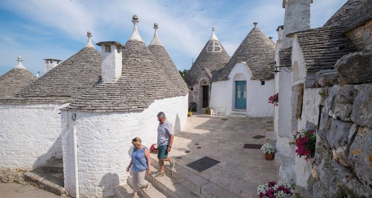 Personas caminando entre casas tradicionales trulli.