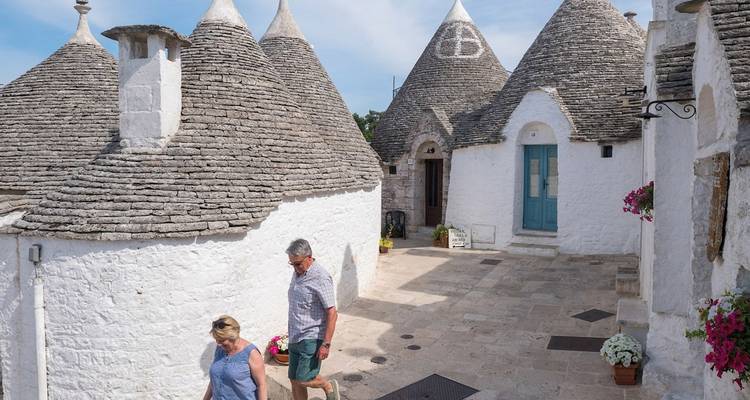 Des visiteurs se promenant entre les maisons trulli coniques blanchies à la chaux avec des toits en pierre à Alberobello.