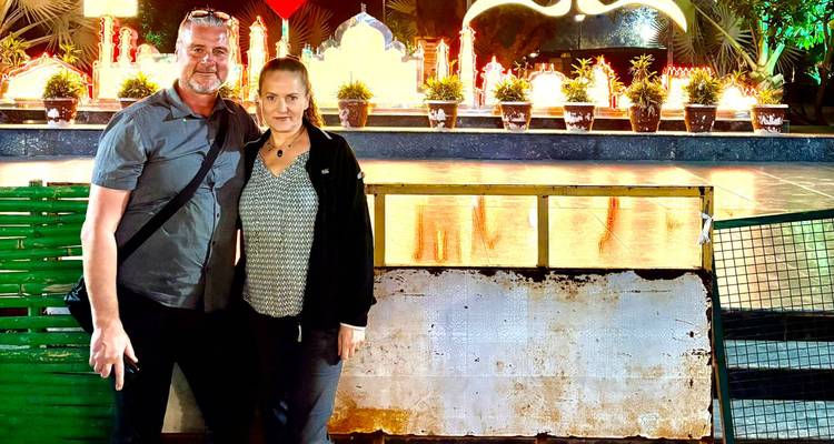 Twee mensen die poseren voor een verlichte structuur 's nachts.