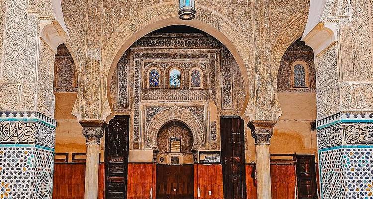 Arcos intrincadamente tallados y azulejería dentro de una madrasa histórica.