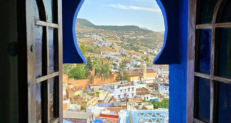 Paisaje urbano pintoresco de Chefchaouen enmarcado por una ventana azul en forma de cerradura.