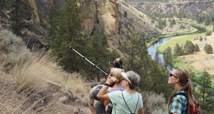 Hikers on a trail with a river view in a canyon.