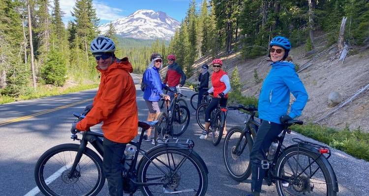 Groupe de cyclistes sur une route forestière avec une montagne en arrière-plan.