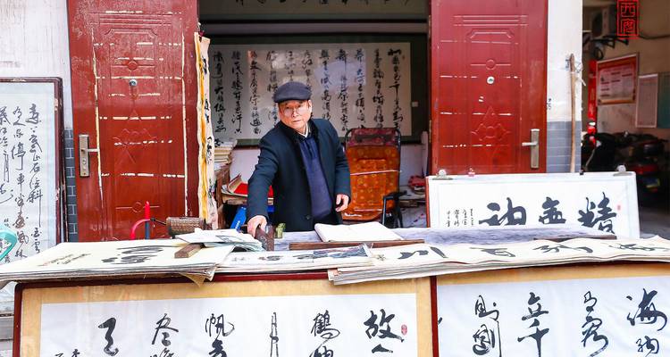 Un calligraphe âgé arrange des rouleaux de caractères chinois à un étal de rue traditionnel