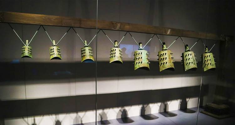 Rangée de cloches de carillon en bronze ancien exposées derrière une vitre dans une galerie de musée