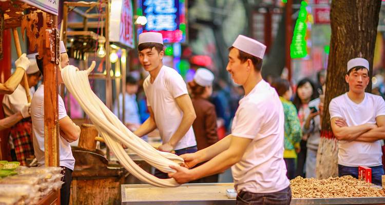 Les chefs étirent de longs brins de nouilles tirées à la main dans une rue animée du quartier musulman