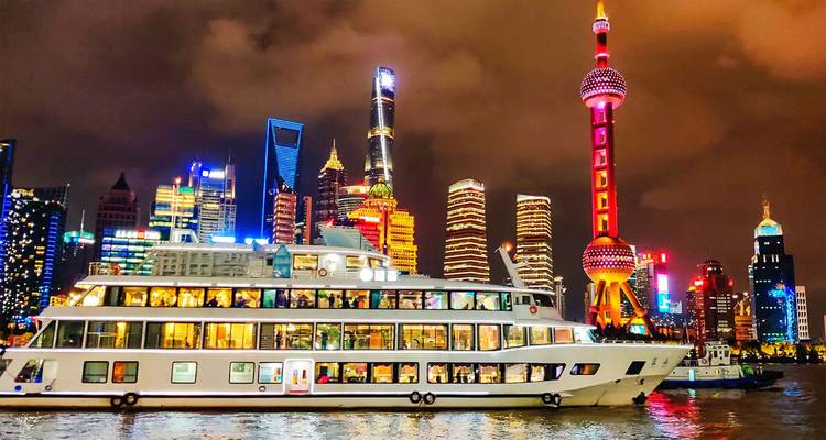 Bateau de croisière fluviale illuminé glissant le long de la skyline néon de Shanghai avec ses tours emblématiques la nuit