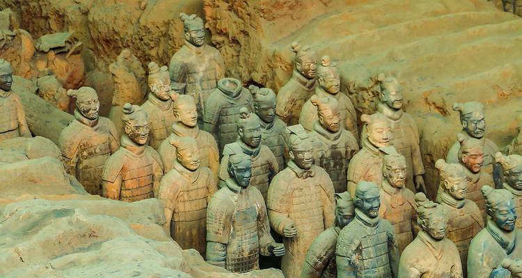 Rangées rapprochées de statues de guerriers en terre cuite de taille réelle se tenant debout dans la fosse d'excavation de couleur terre.