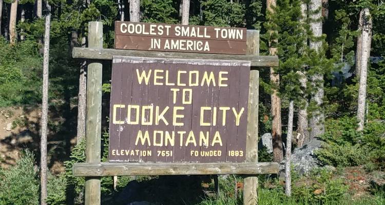 Panneau accueillant les visiteurs à Cooke City, Montana avec des arbres en arrière-plan.