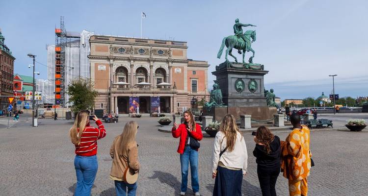 Stadtrundfahrtsgruppe hört in der Nähe einer Reiterstatue auf einem großen europäischen Platz zu.