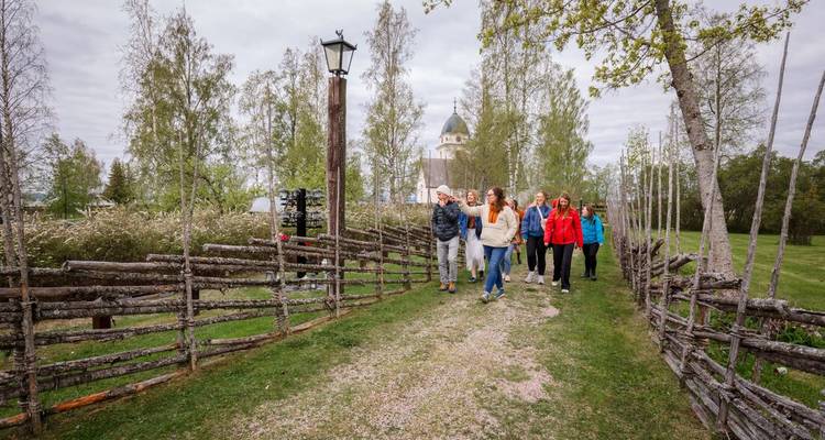 Geführte Gruppenrundgänge führen über einen Kiesweg zwischen rustikalen Zäunen zu einer Kirche mit weißer Kuppel.
