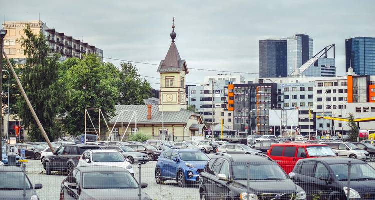 Vue de voitures garées dans un parking avec des gratte-ciel de la ville en arrière-plan.