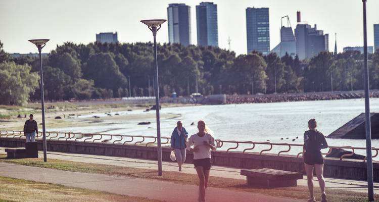 Des gens qui font du jogging le long d'un sentier au bord de l'eau avec des gratte-ciel de la ville.