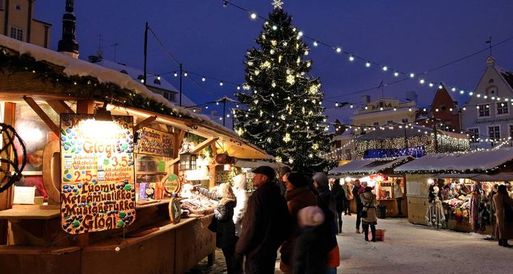 Des personnes explorent le marché de Noël avec un grand sapin et des lumières.