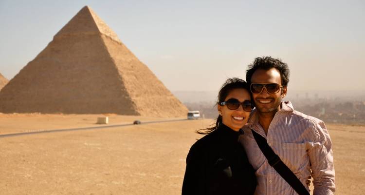 Couple posant avec une pyramide en arrière-plan.